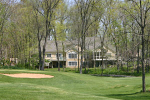 A two-story house shrouded by trees and overlooking the Cress Creek golf course.