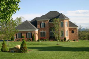 A two-story brick house with bay windows, a large lawn and beautiful landscaping.