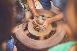 A potter working a lump of clay on a pottery wheel.