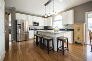 Modern kitchen interior with bar seating and hardwood floors.