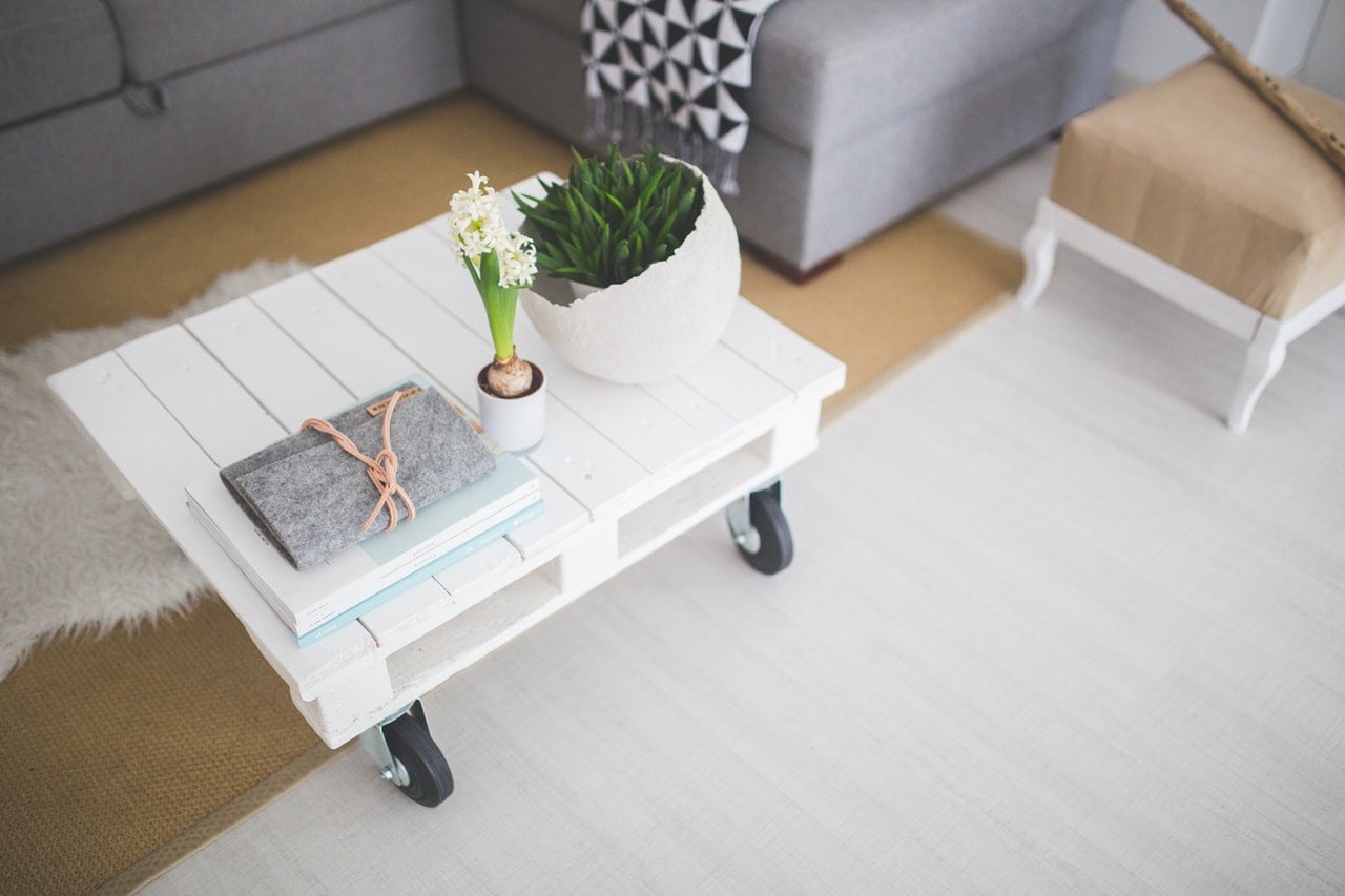 A small table in a living room neatly organized with a journal, and two plants.