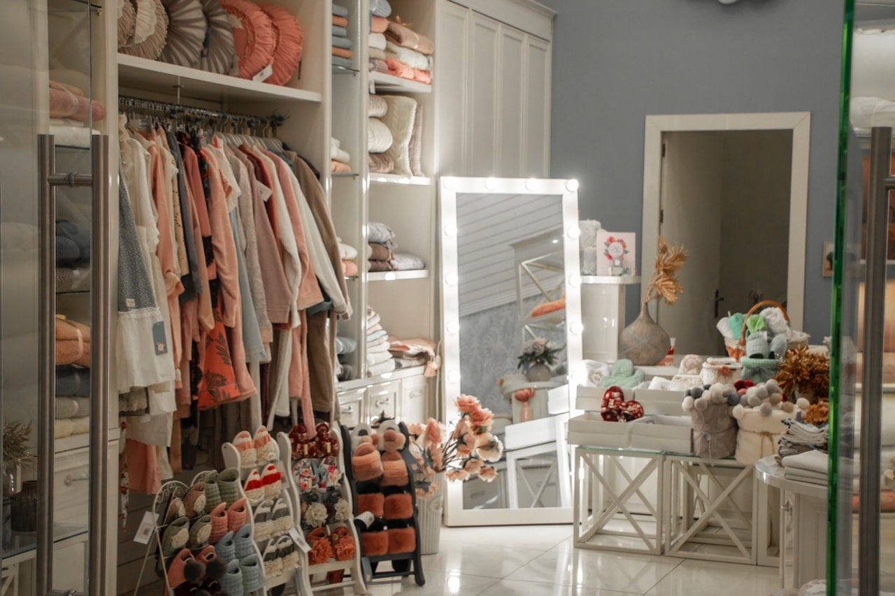 A woman's bedroom filled with clothes, shoes, and miscellaneous items.
