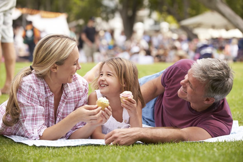 A family of three enjoying cupcakes at an event.