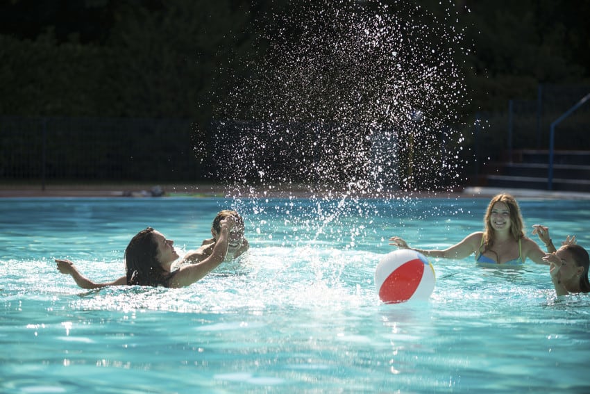 Kids playing in a pool during the summer.