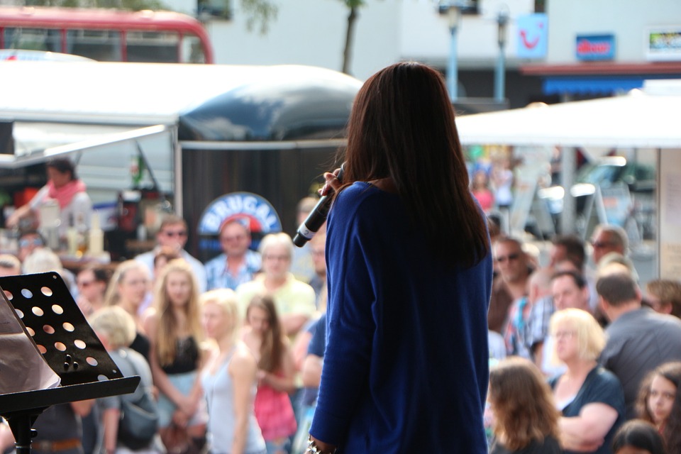 A woman talking on stage at a festival.