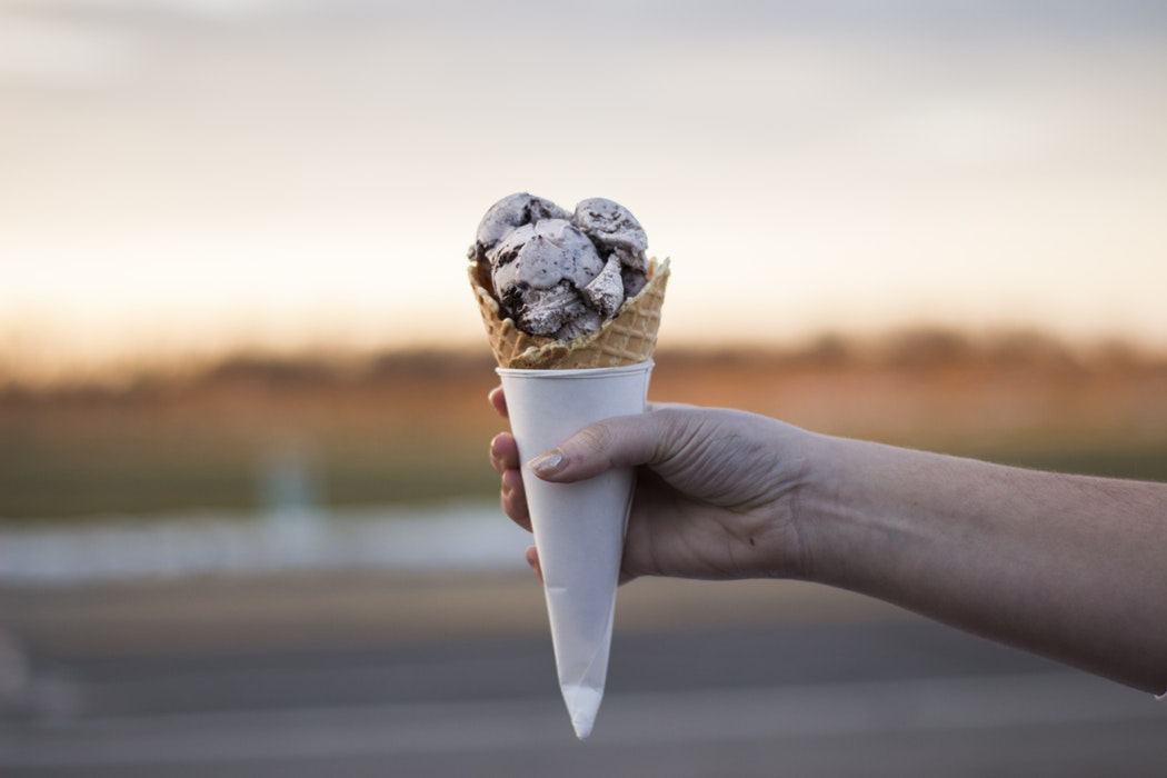 A person holding up an ice cream cone.