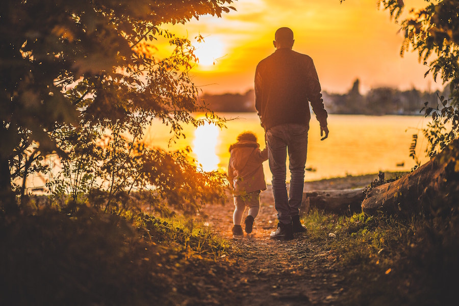 Adult and child enjoying sunset on the lake.