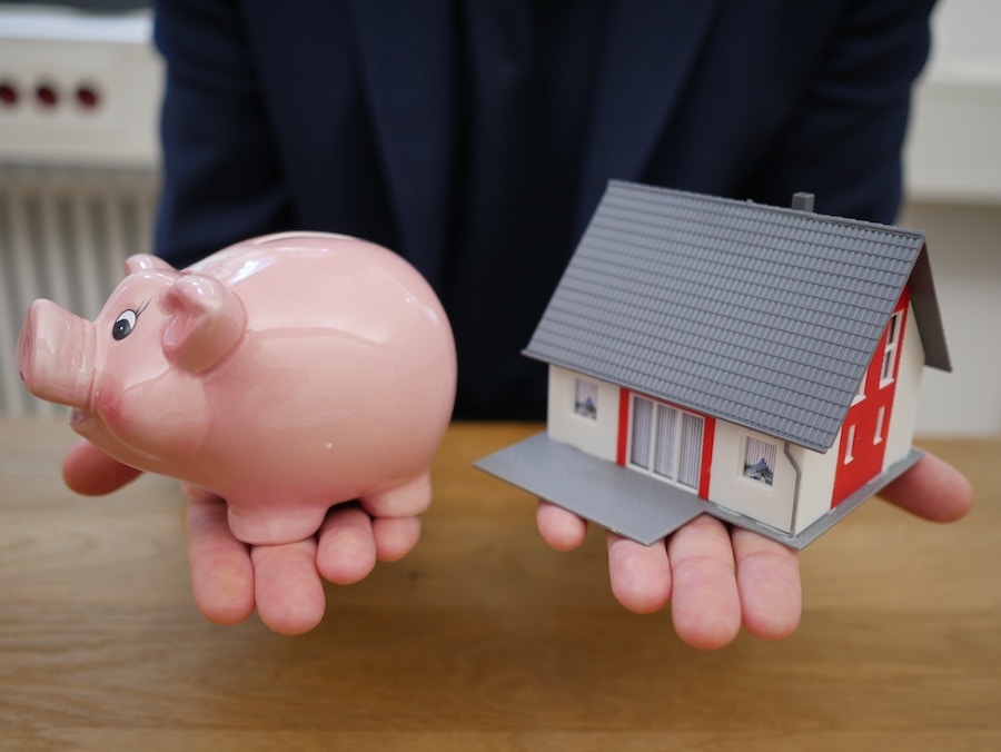 Person holding house and piggy bank